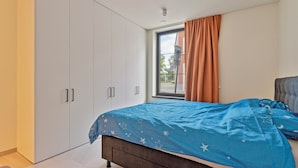 Une chambre à coucher avec un lit, une armoire et une fenêtre avec des rideaux.