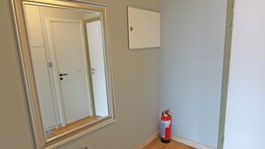 A room with a large mirror, a fire extinguisher, and a door.