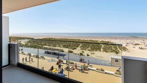 Un balcon avec vue sur une plage et des dunes.