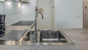 Eine moderne Küche mit Spüle aus Edelstahl, einem Wasserkocher und einer Mikrowelle.