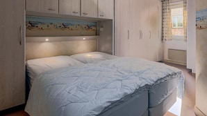 Ein Schlafzimmer mit einem Bett, einem Holzschrank und einem Bild über dem Bett.