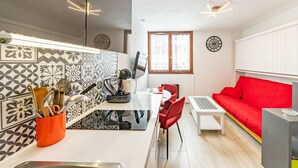 A compact living space with a kitchen, dining area, and a red sofa. - Modern and cozy studio at the chairlift's base (Saint-François-Longchamp)