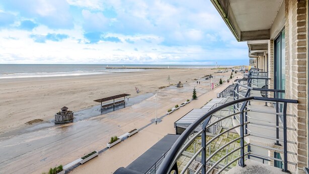 A balcony with a view of a beach and pier.
