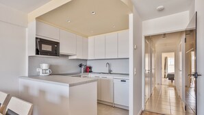 A modern kitchen with white cabinetry, a built-in microwave, and a coffee maker. - 2 bedroom accommodation in Nieuwpoort (Nieuwpoort)