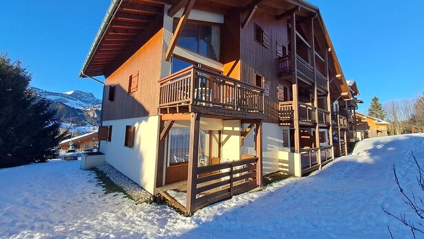 A multi-story wooden chalet with balconies, set in a snowy landscape with mountains in the background. - Central 1-bedroom apartment, well equipped with WIFI (Crest-Voland)