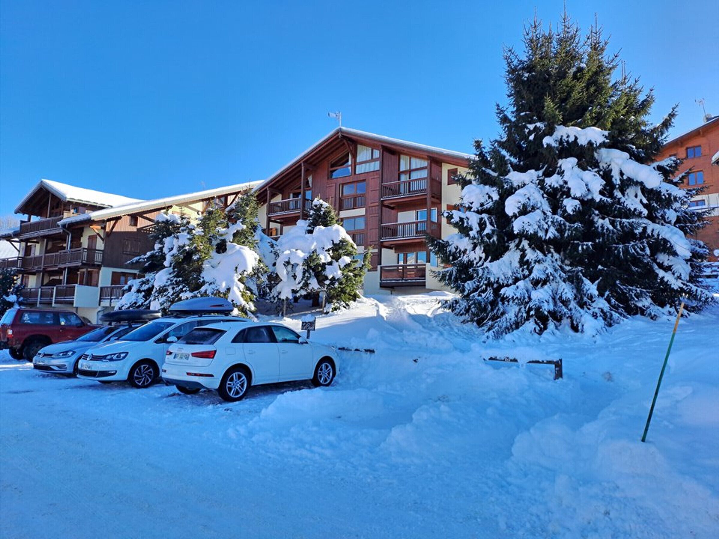 A hotel with multiple floors, balconies, and a parking area with several cars.