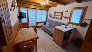 A compact kitchen with a dining table, a sofa, and a small countertop. - Central 1-bedroom apartment, well equipped with WIFI (Crest-Voland)