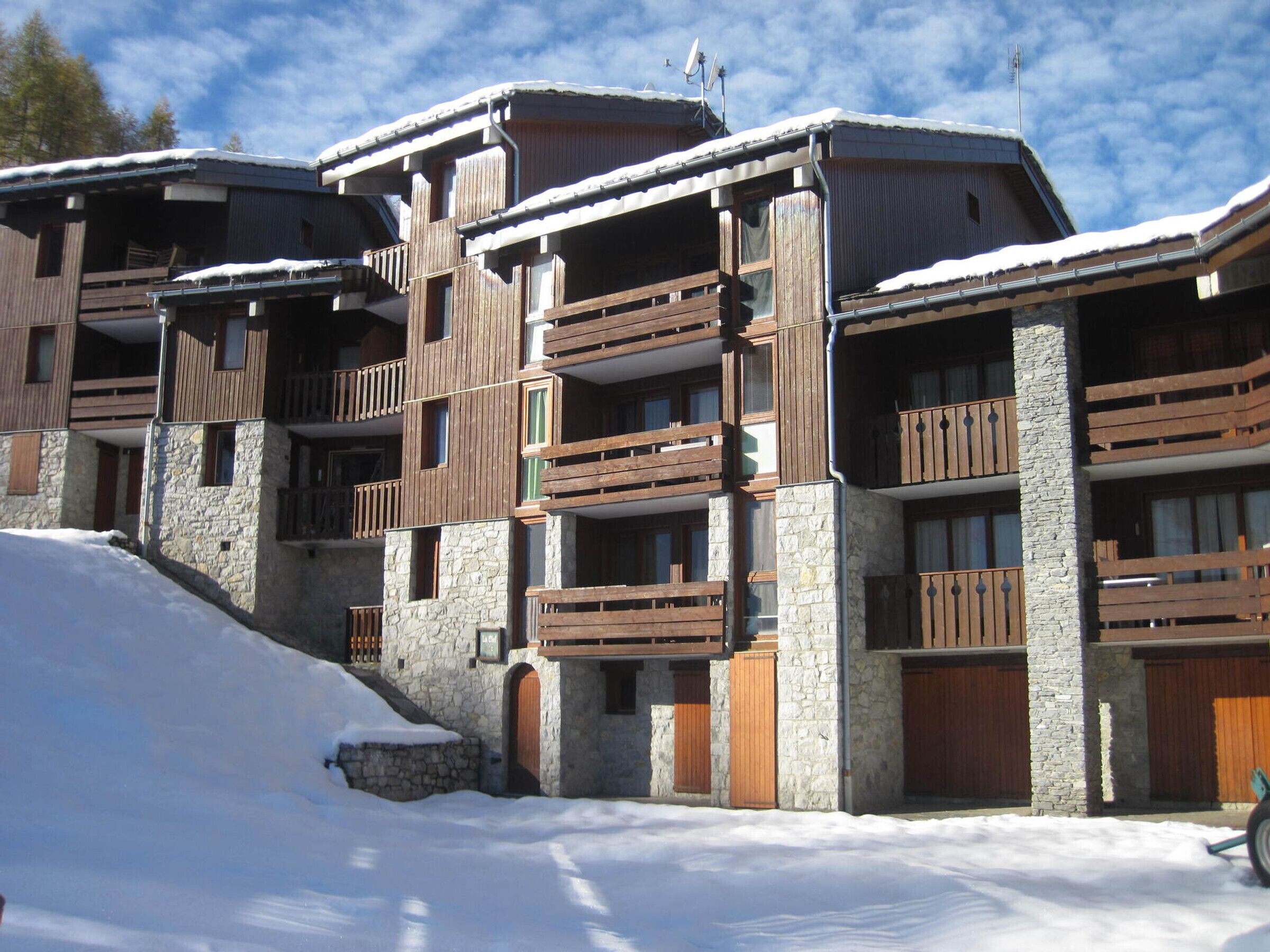 Un hôtel à plusieurs étages, avec une façade en pierre et en bois, des balcons et un paysage enneigé.