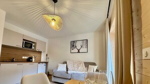 En moderne stue med et træspisebord, en sofa og et køkkenområde med en mikrobølgeovn.