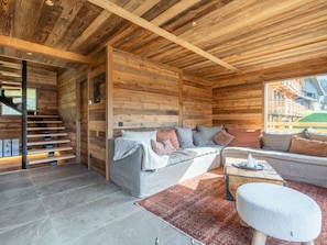 A log cabin interior with a sofa, a table, and a staircase.