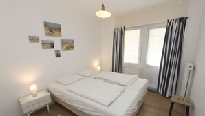 A bedroom with a bed, nightstands, a lamp, a window with curtains, and wall art.
