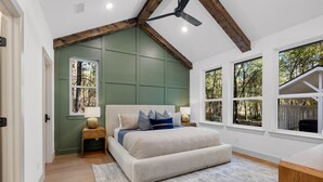 Un dormitorio con una cama grande, un ventilador de techo y varias ventanas.