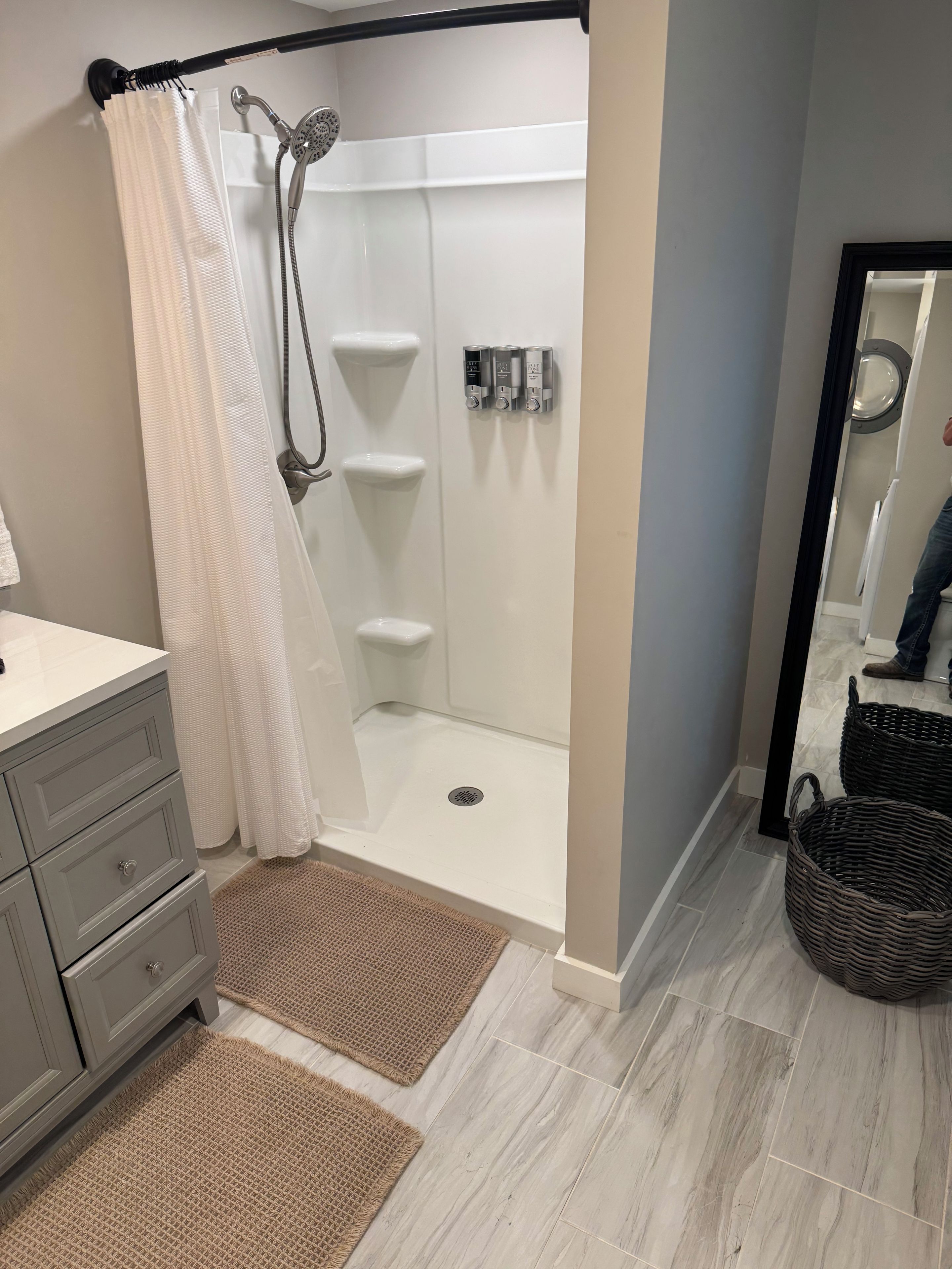 Une salle de bain moderne équipée d’une douche, d’un meuble-lavabo et d’un miroir.