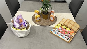 A dining table with a fruit basket, a potted plant, a tray of sandwiches, and a bowl of pastries. - Apartment Rome center (Roma)