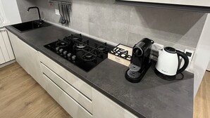 A modern kitchen with a gas stove, a coffee maker, and a kettle. - Apartment Rome center (Roma)