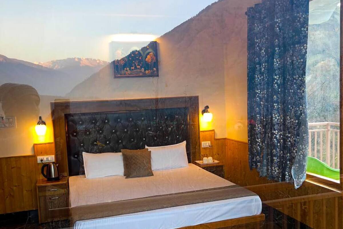Une chambre avec un grand lit, une tête de lit en bois, deux tables de chevet avec des lampes, un tapis moelleux et une table basse en verre.