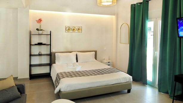 Ein modernes Hotelzimmer mit Bett, Sofa, kleinem Tisch und Fernseher.
