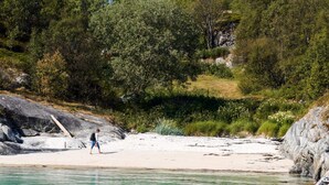 A beach with clear water, a wooden ladder, and rocky terrain. - 3 Person Holiday Home in Tranoy (Hamaroy)