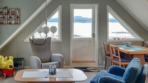 A cozy loft bedroom with a large window overlooking a body of water, a comfortable bed, and a small desk area. - 3 Person Holiday Home in Tranoy (Hamaroy)