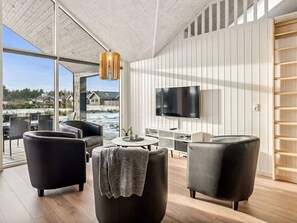 A modern living room with a large TV, comfortable seating, and a view of a snowy landscape.