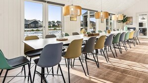 Un comedor moderno con una mesa larga, varias sillas y lámparas colgantes.