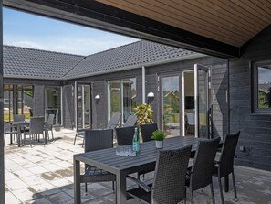 An outdoor patio area with a table and chairs, a potted plant, and a sliding glass door leading to an interior space. - 5 Star Holiday Home in Norre Nebel (Norre Nebel)