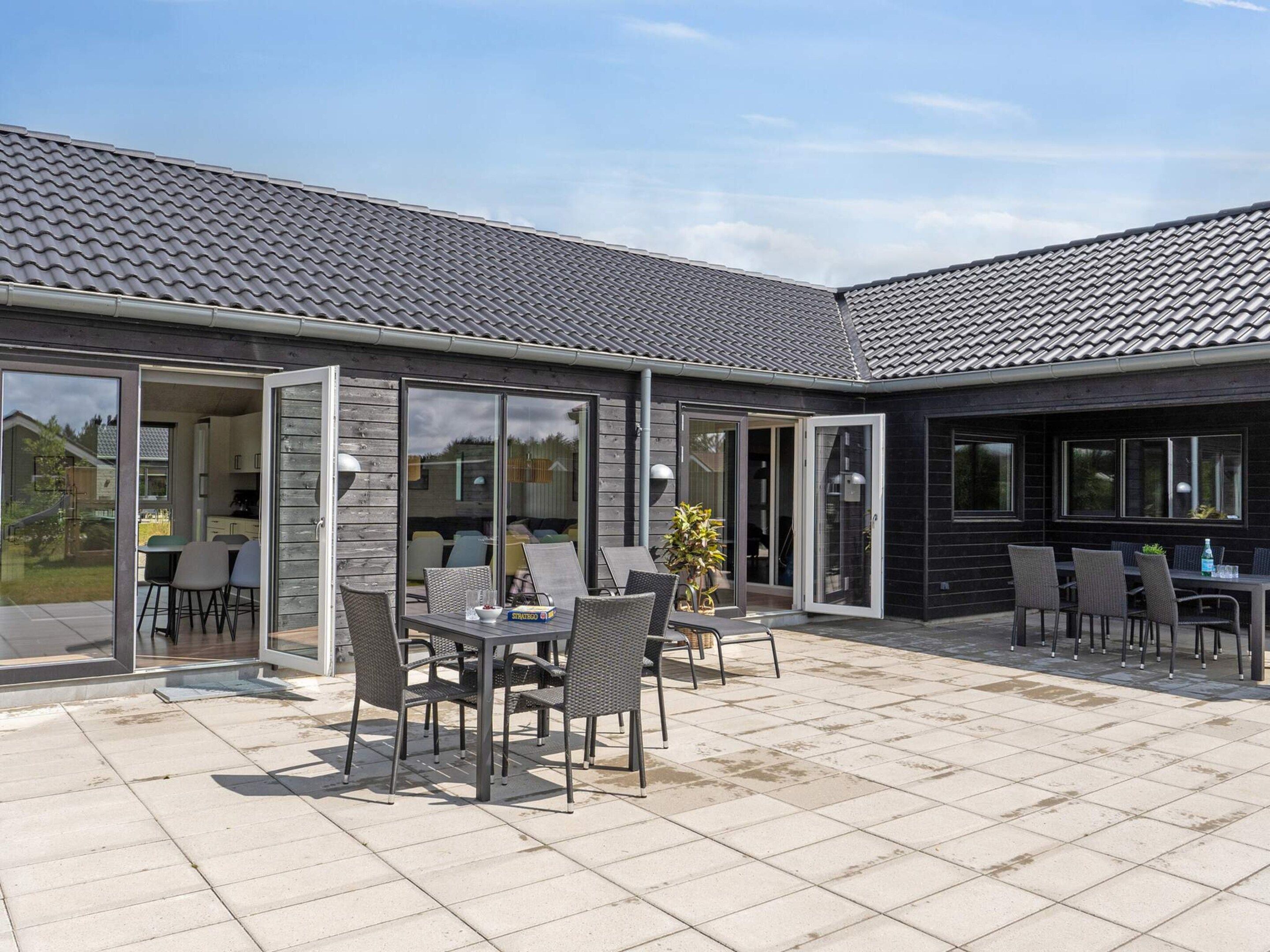 Een modern gebouw met een patio, voorzien van buitenmeubels en een eettafel.