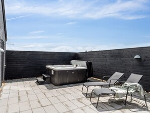 A rooftop patio with a hot tub, lounge chairs, and a tiled floor. - 5 Star Holiday Home in Norre Nebel (Norre Nebel)