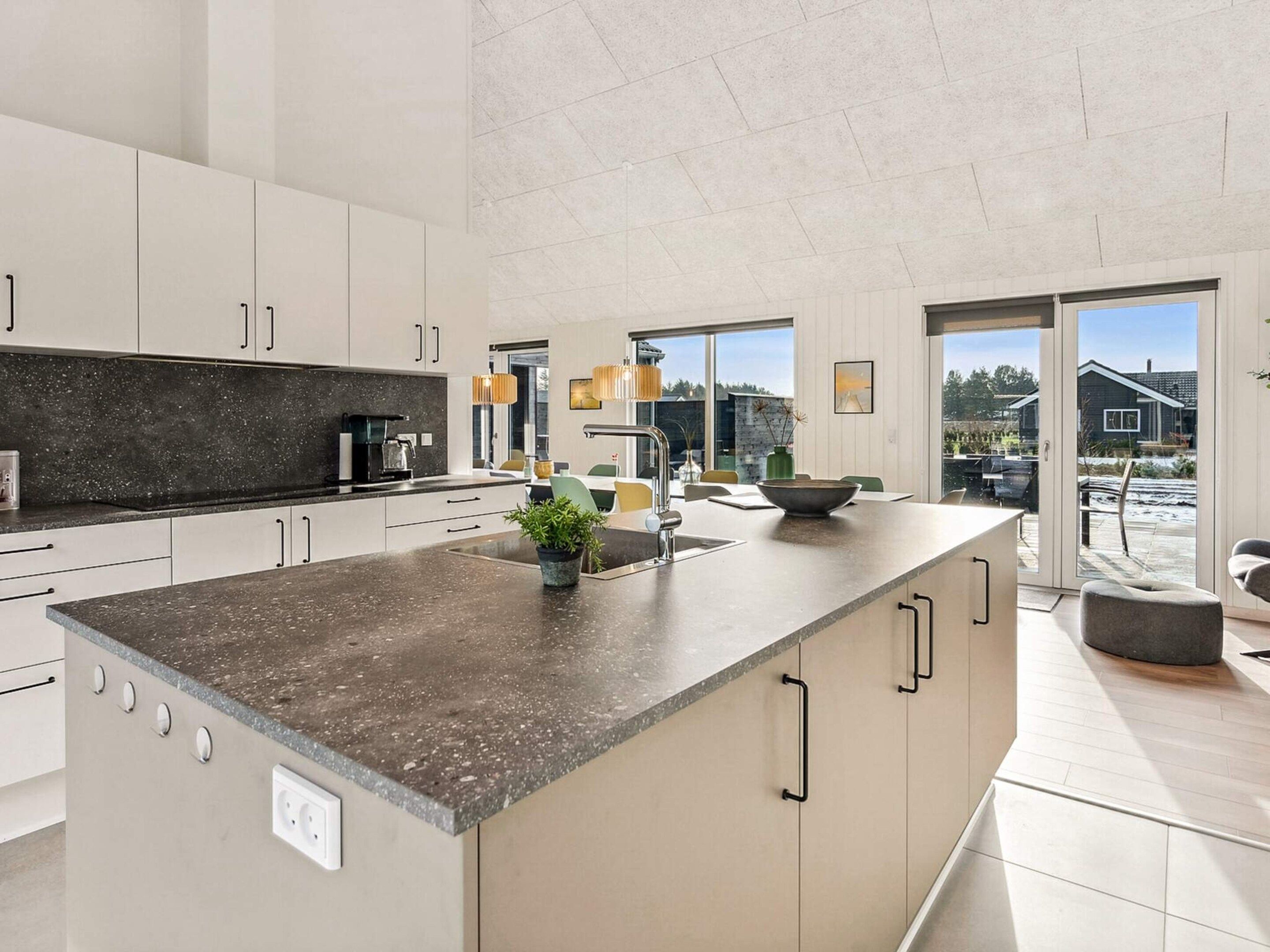A modern kitchen with a large island, built-in appliances, and a view to the outdoors.