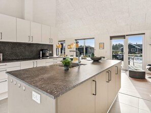 A modern kitchen with a large island, built-in appliances, and a view to the outdoors. - 5 Star Holiday Home in Norre Nebel (Norre Nebel)