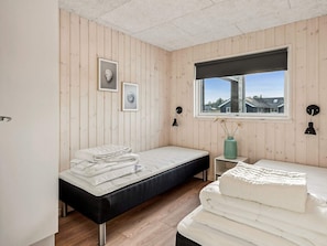 A bedroom with two beds, a window with a view, and wall-mounted lamps.