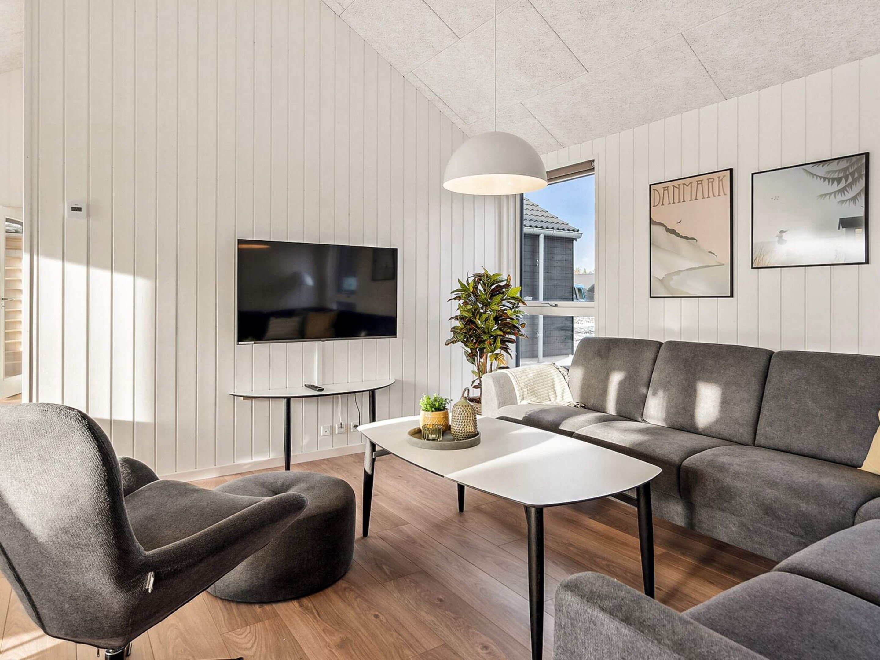 A modern living room with a flat-screen TV, grey sofa, and a coffee table.