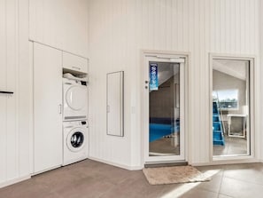 A laundry room with a washing machine, a dryer, and a door leading to a balcony.