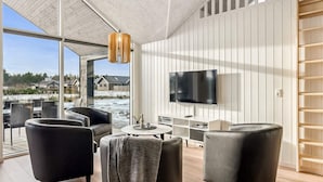 Una sala de estar moderna con un televisor grande, asientos cómodos y vistas a un paisaje nevado.
