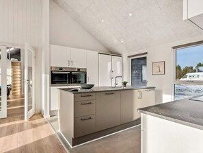A modern kitchen with built-in appliances, a large island, and a view of the outside.