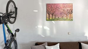 Une pièce dans laquelle on peut voir un vélo posé sur un support, un tableau représentant des fleurs de cerisier accroché au mur et un canapé marron.