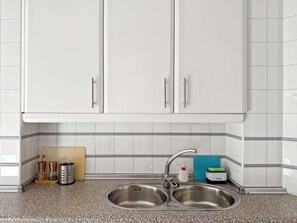 Cocina con armarios blancos, un lavamanos de acero inoxidable doble y encimera de granito.