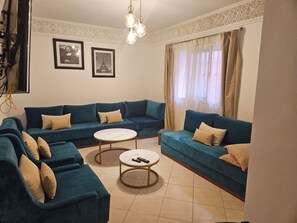 Ein Wohnzimmer mit einer Eckcouch, einem runden Couchtisch und zwei gerahmten Bildern an der Wand.