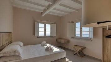 A bedroom with a bed, two windows, a wooden bench, and a hanging coat rack.