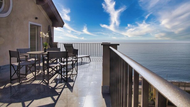 A balcony with a view of the sea, a table with chairs, and a potted plant. - Campetti (Genoa)