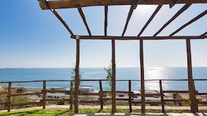 A wooden pergola with a stone floor, overlooking a coastal view with the sea and a distant cityscape. - Campetti (Genoa)