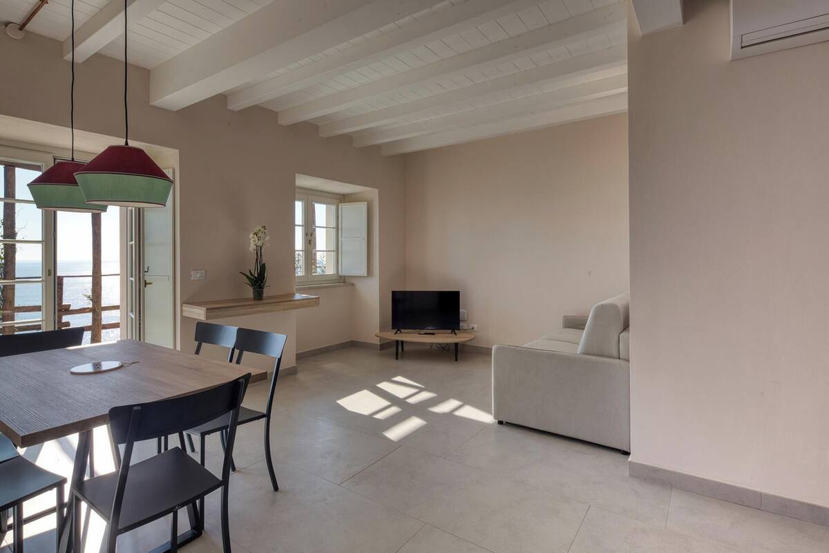 A spacious living area with a dining table, chairs, a sofa, and a TV.