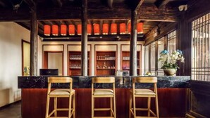 A bar area with three wooden bar stools, a marble countertop, and shelves with glasses and bottles. - ESGBihu Digital Nomad Cowork Colive Hub (Lishui)