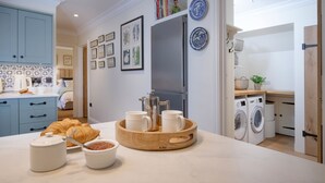 A modern kitchen with a breakfast setup including croissants, coffee, and a fruit bowl.