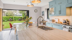 Een moderne keuken met een groot eiland, roestvrijstalen apparatuur en lichtblauwe kastjes.