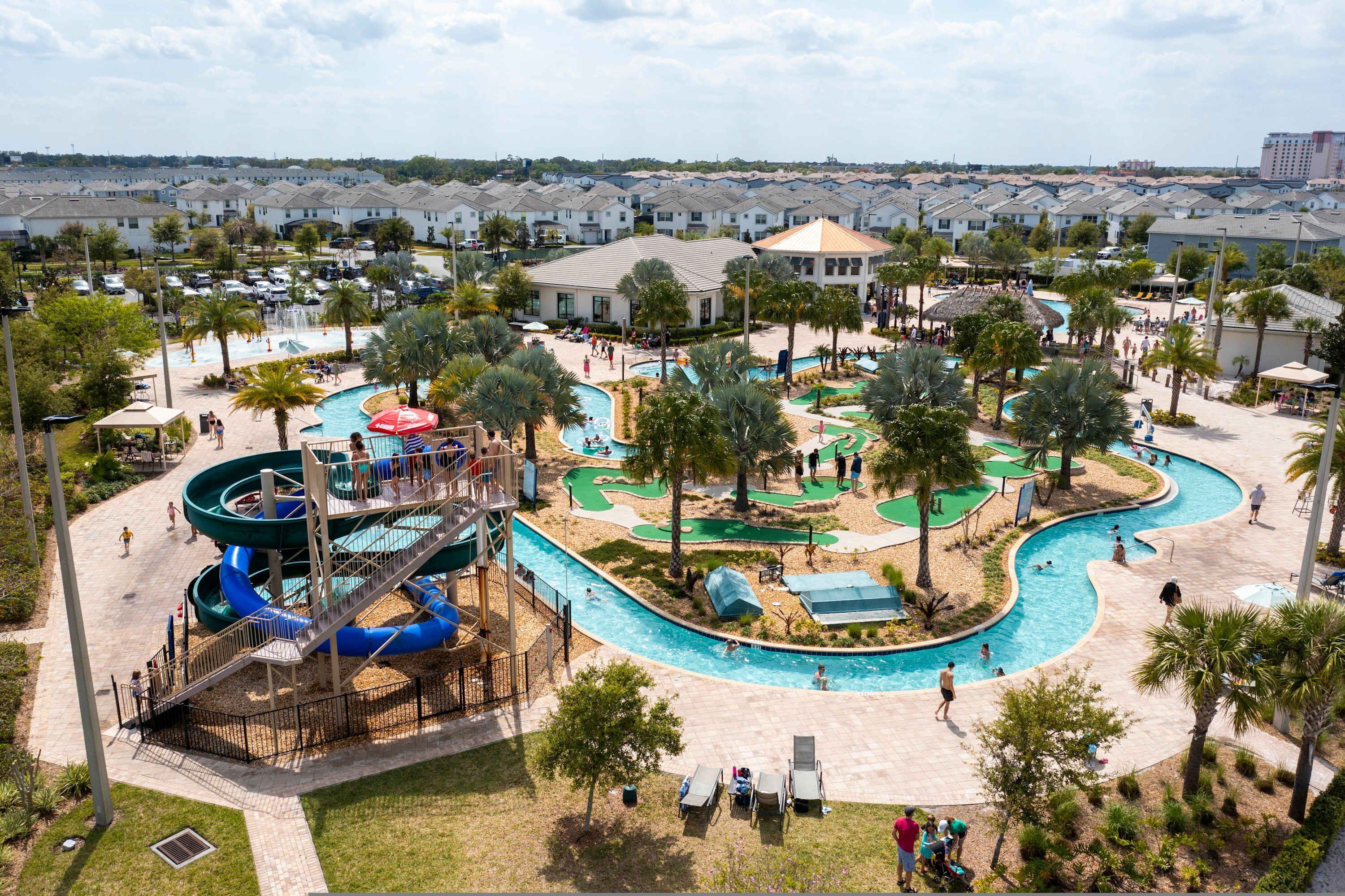 A resort with a large pool area, a water slide, and a golf course.