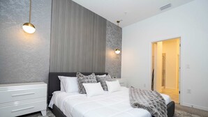 Een moderne slaapkamer met een groot bed, nachtkastjes en een kledingkast.