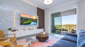 Een moderne woonkamer met een flatscreen televisie, een rond bijzettafeltje en een grote bank.