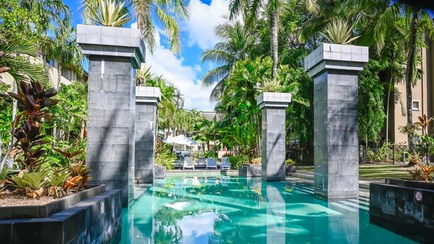 A swimming pool with a depth of 1.0m, surrounded by palm trees and lounge chairs. - Coral Luxe Resort - 9 Pools Gym BBQ (Westcourt)
