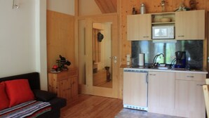 Ett kompakt kök med träskåp, en mikrovågsugn och en kaffebryggare. En dörr leder in till ett annat rum.